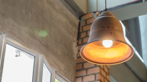 Low angle view of illuminated pendant light hanging on ceiling in building