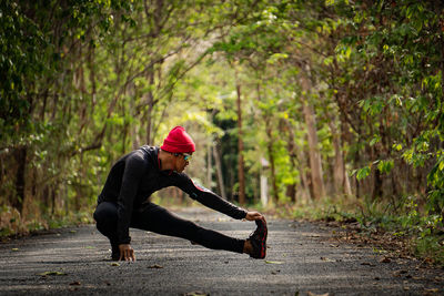 Man exercising on road in forest
