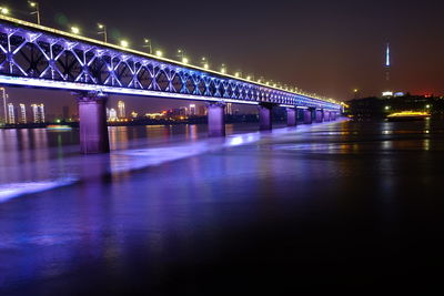 Illuminated bridge over river at night