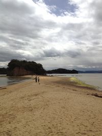 Scenic view of beach against cloudy sky