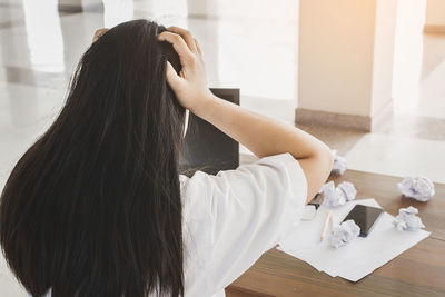 Rear view of woman holding paper at home