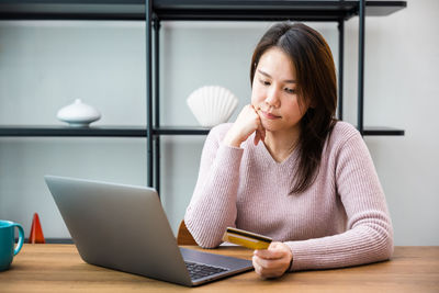 Young woman using laptop while sitting on table