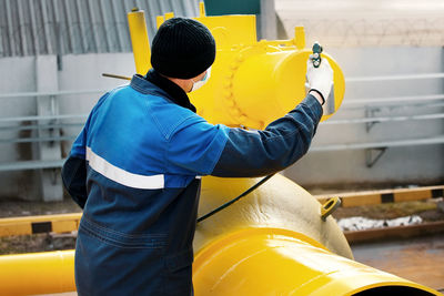 Rear view of man holding yellow umbrella