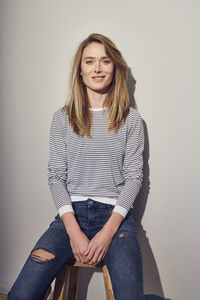 Portrait of smiling woman sitting on stool