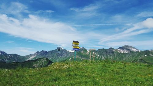 Road sign on landscape against sky