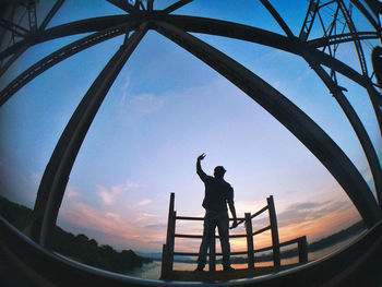 Rear view of silhouette man photographing at sunset