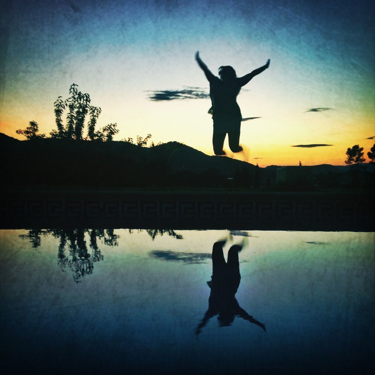 silhouette, full length, jumping, water, mid-air, sky, reflection, sunset, lifestyles, leisure activity, men, waterfront, built structure, standing, arms outstretched, outdoors, architecture, arms raised