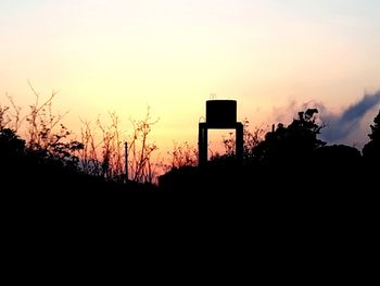 Silhouette of water tower against sky during sunset