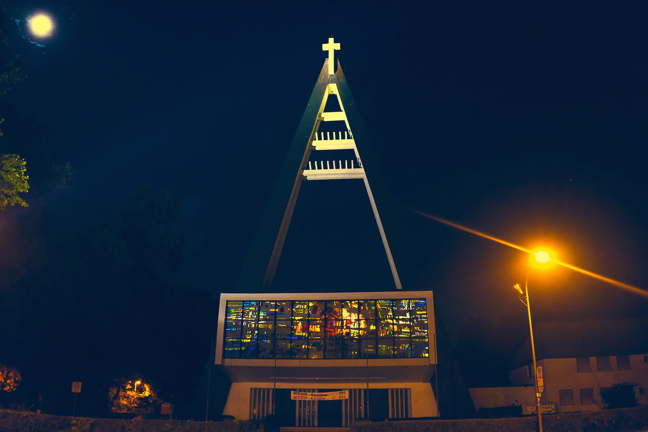 low angle view, illuminated, night, built structure, architecture, clear sky, sky, building exterior, lighting equipment, blue, no people, outdoors, copy space, dusk, tree, high section, building, light - natural phenomenon, railing, street light