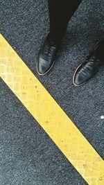 Low angle view of person standing on road by yellow dividing line