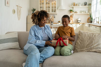 Mother using laptop while sitting on sofa at home