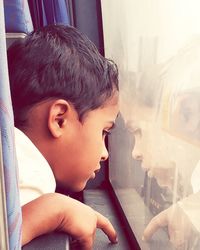 Close-up portrait of boy looking through window