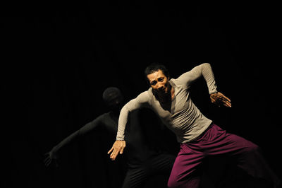 Midsection of man dancing against black background