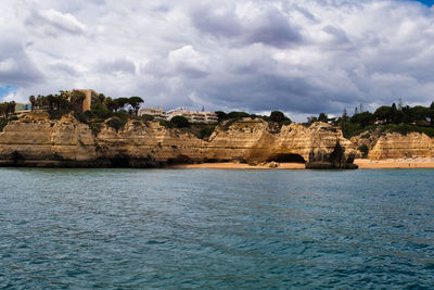 View of sea and rocks against cloudy sky