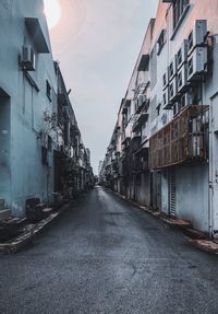 Empty road amidst buildings against sky