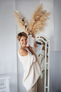 Beautiful woman decorates house bouquet of cotton and dry grass. happy and laughing