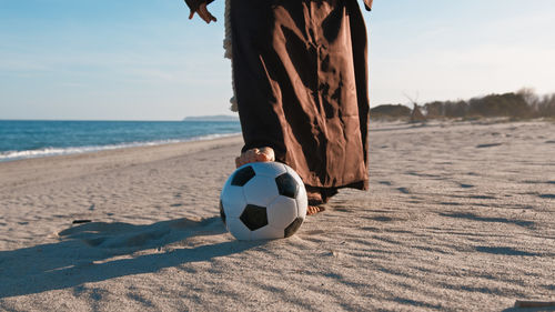 Rear view of man playing soccer at beach