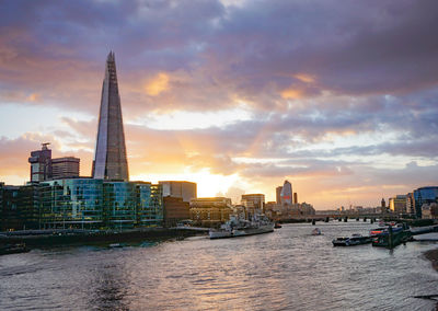 View of buildings at waterfront against cloudy sky