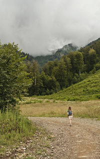 Rear view of man walking on mountain road