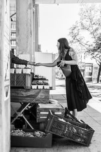 Side view of woman shopping from market stall