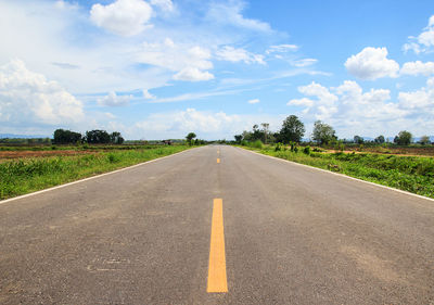 Road amidst field against sky