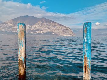 Wooden posts in sea against sky