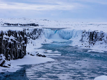 Scenic view of waterfall against sky during winter