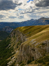 Wavy plateau with the cliff high in mountains and heavy rainy clouds in the sky.