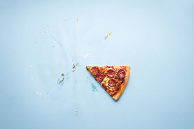 Directly above shot of pizza slice on blue background