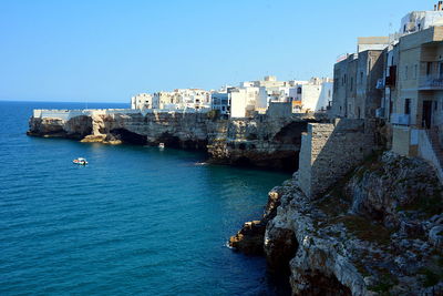 Sea by buildings against clear blue sky
