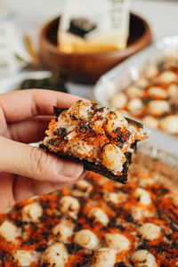 Close-up of hand holding meat on barbecue grill
