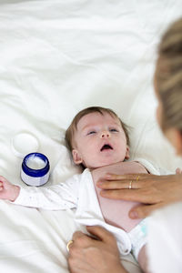 Cropped hand of woman applying cream on son belly
