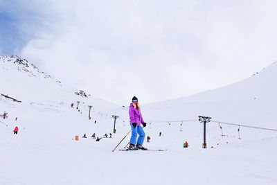 Woman skiing on snow covered field against sky