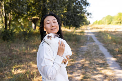 Portrait of young asian woman holding a white rabbit in park