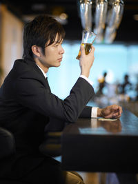 Side view of young businessman drinking at bar