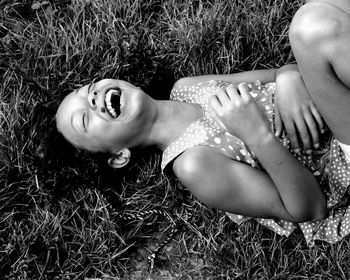 High angle view of happy girl laughing while lying down on grassy field