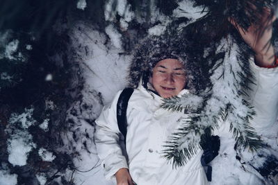Directly above shot of woman lying down amidst plants on snow