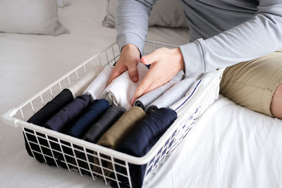 Midsection of woman sitting on bed at home