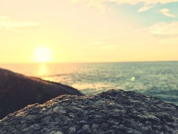 Close-up of rocks by sea against sky during sunset