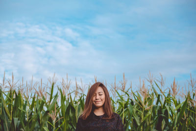 Smiling beautiful woman standing at farm against sky