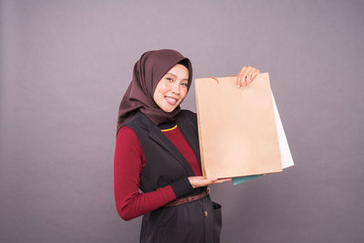 Portrait of smiling young woman standing against white background