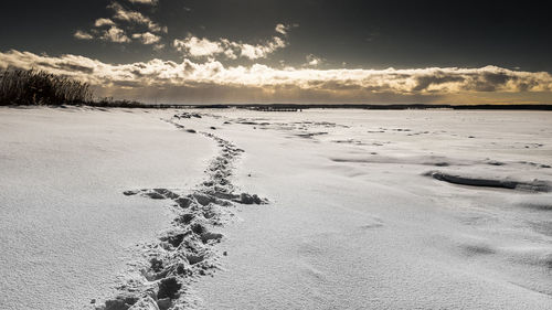 Scenic view of frozen beach against sky during sunset