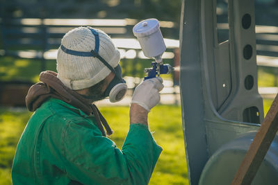 Portrait of man holding hat on field