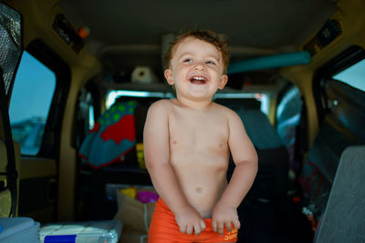 Portrait of shirtless boy in car