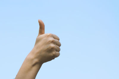 Low angle view of human hand against clear sky