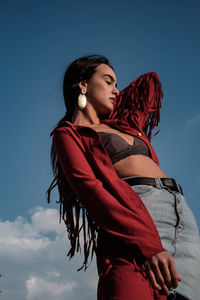 Low angle view of young woman standing against blue sky