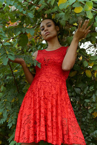 Beautiful young woman standing against plants