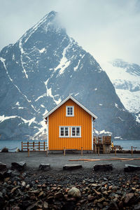 House by snowcapped mountains against sky