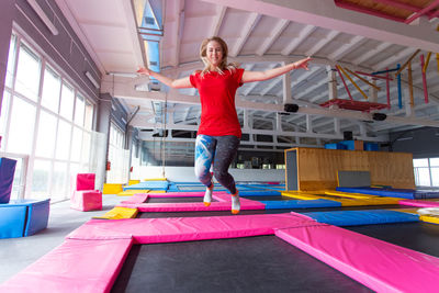 Full length portrait of woman standing against multi colored ceiling