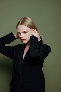 Portrait of young businesswoman standing against wall